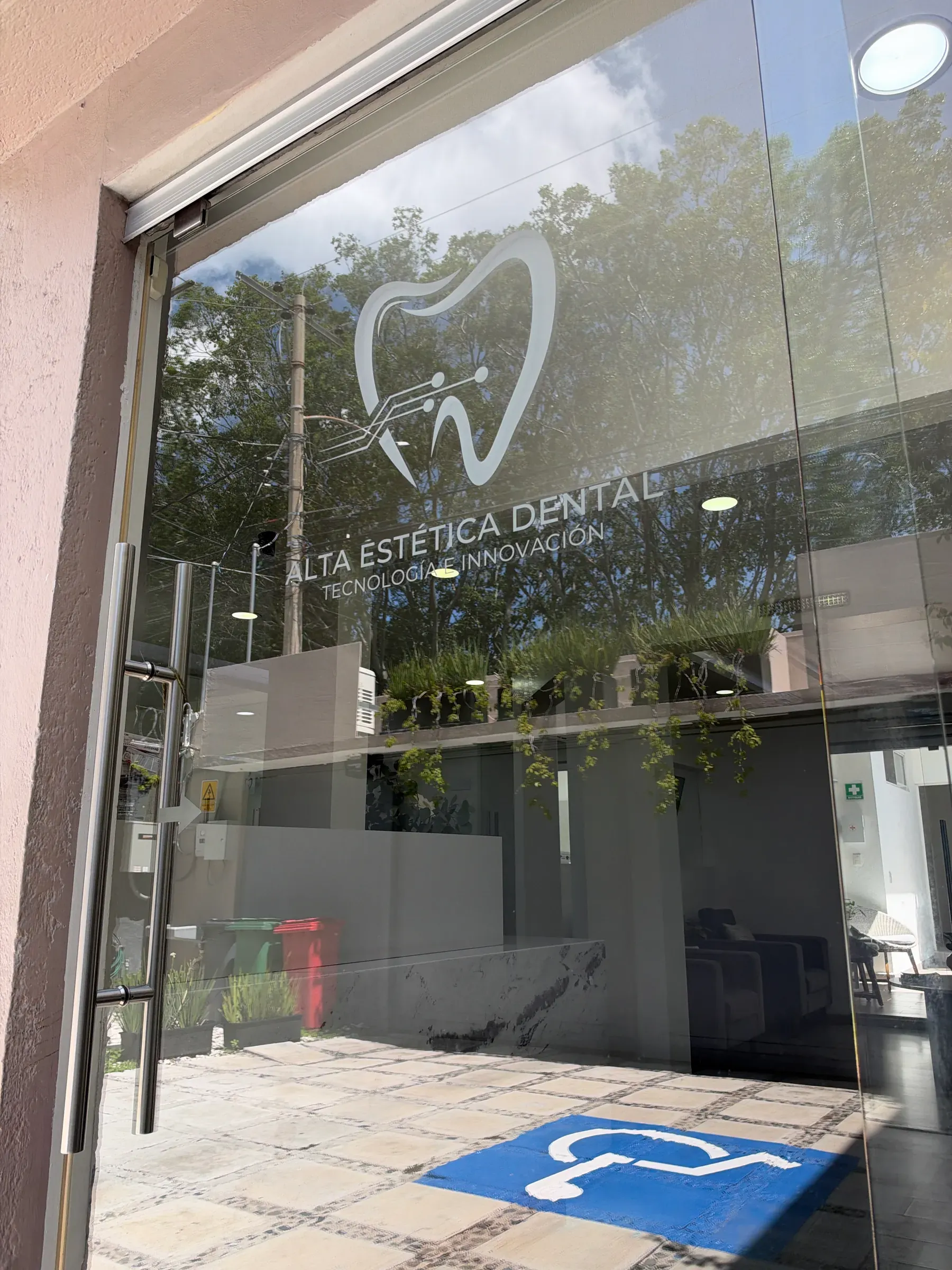 Puerta de cristal con el logotipo de la clínica y el símbolo de acceso para silla de ruedas en el piso.