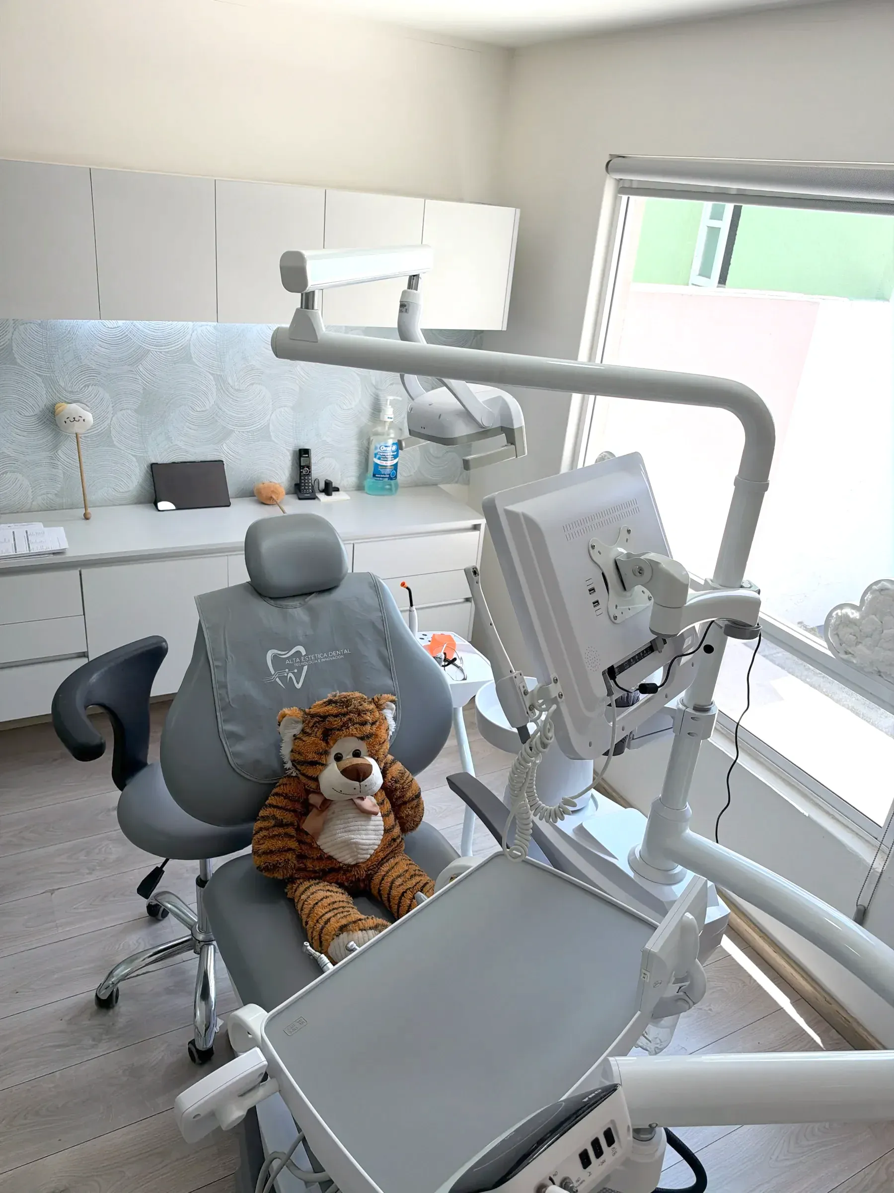 Consultorio con un peluche sentado en el sillón dental.