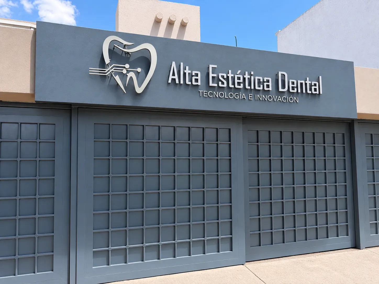 Fachada de Alta Estética Dental, con el letrero de la clínica sobre el portón gris.