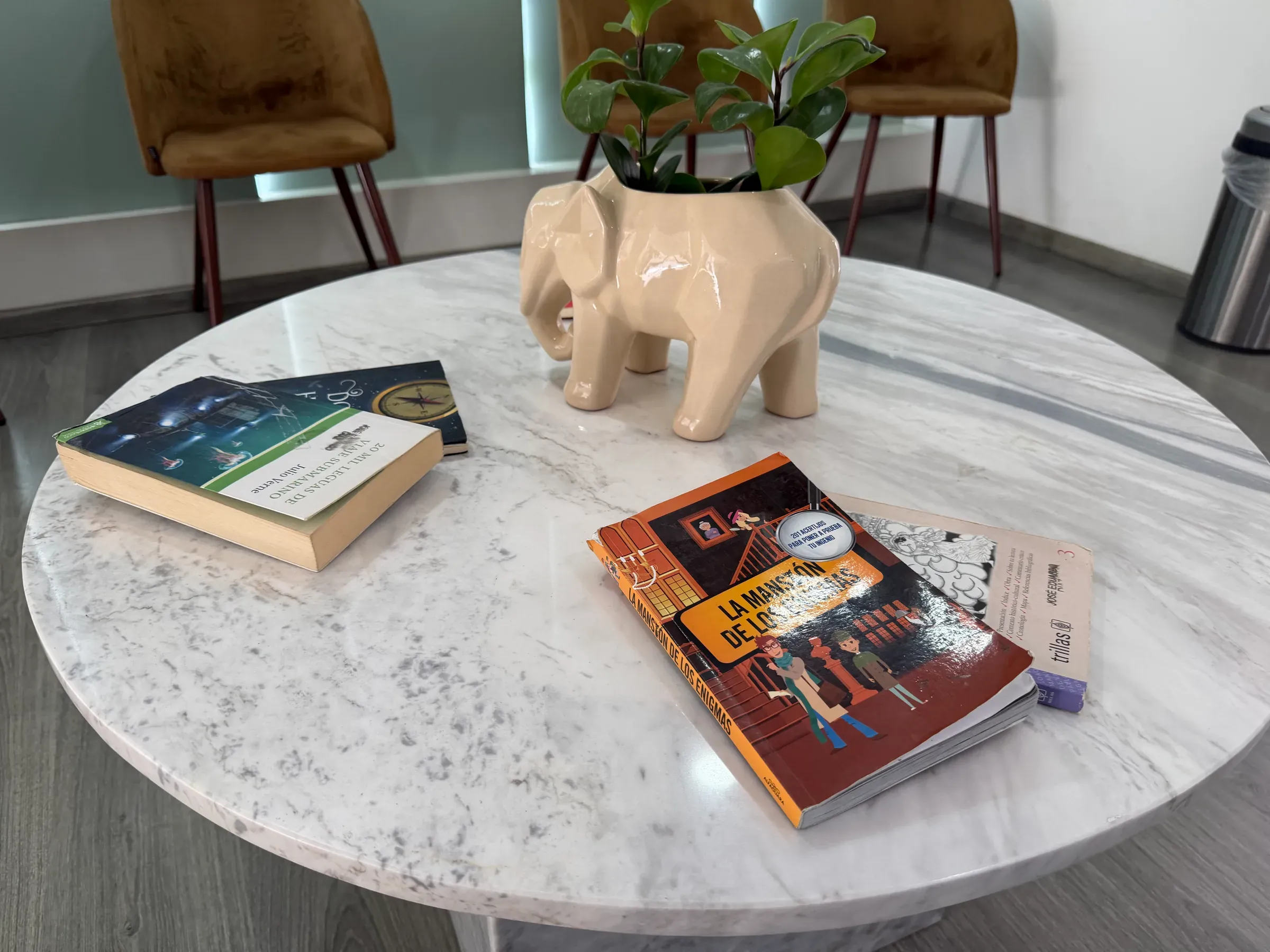 Mesa de centro de mármol con libros y una maceta en forma de elefante.
