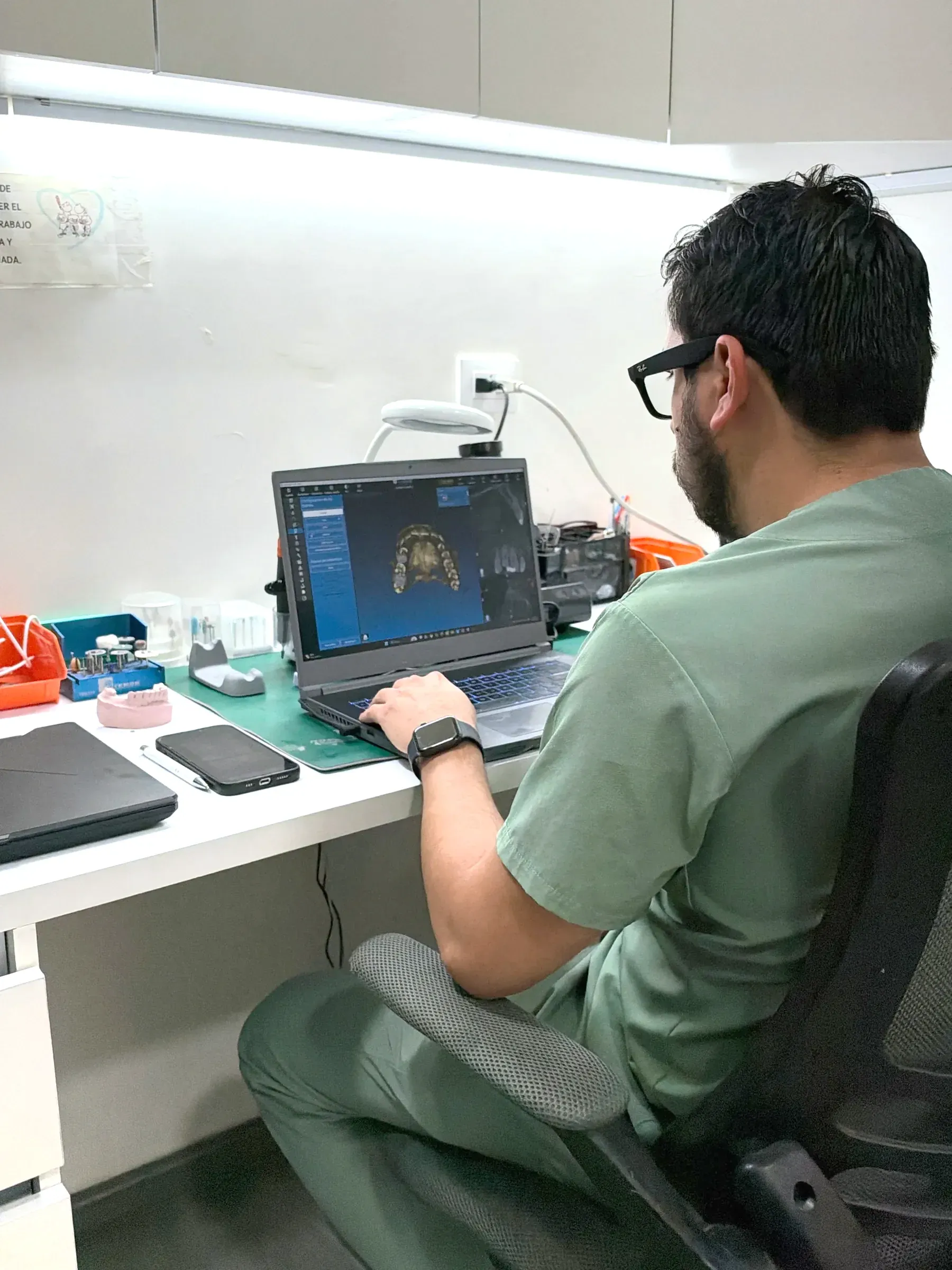 Técnico del laboratorio de la clínica diseñando una restauración en la computadora.