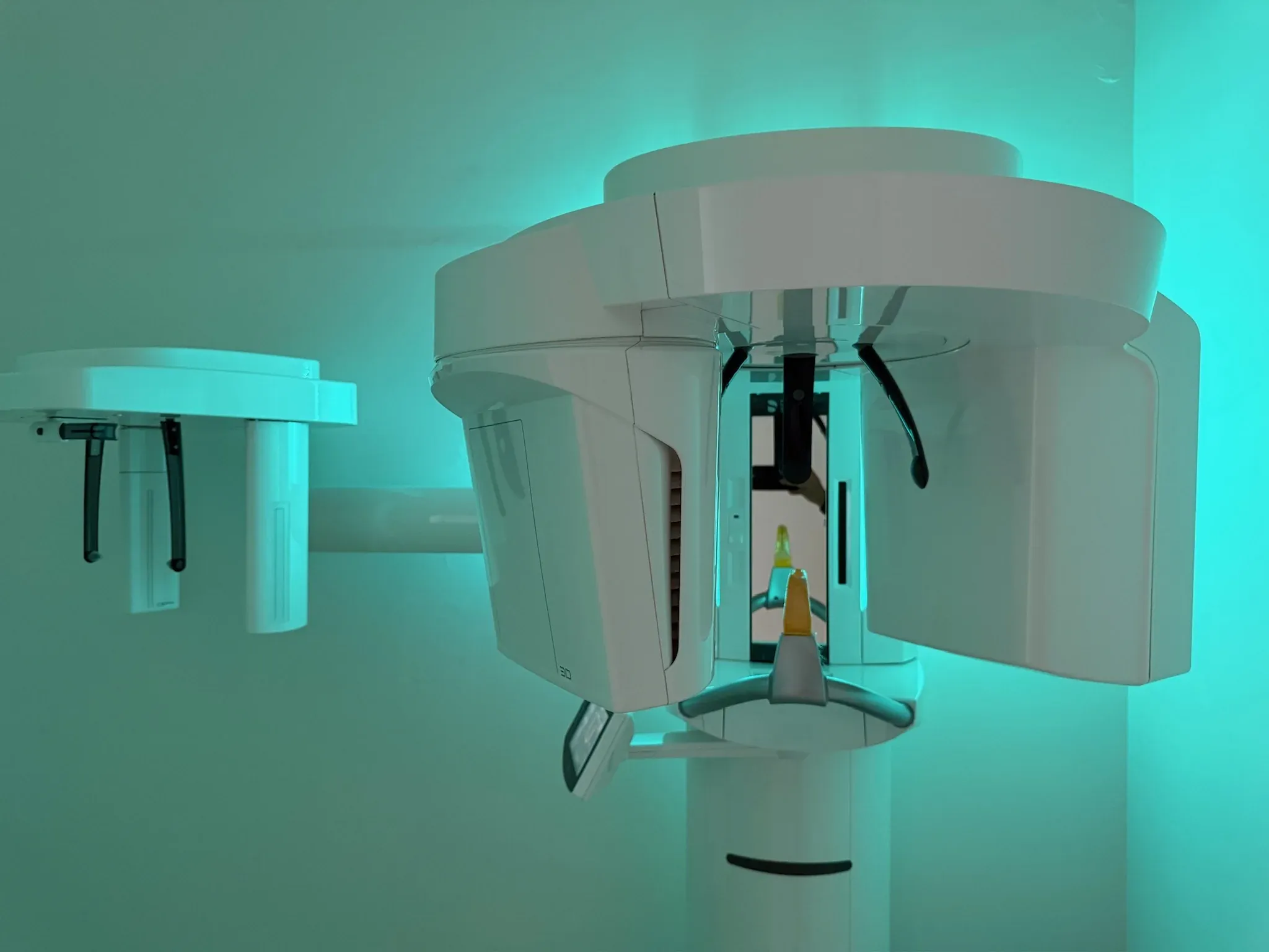 Tomógrafo 3D de Dentsply Sirona en su sala de la clínica, iluminado en turquesa.