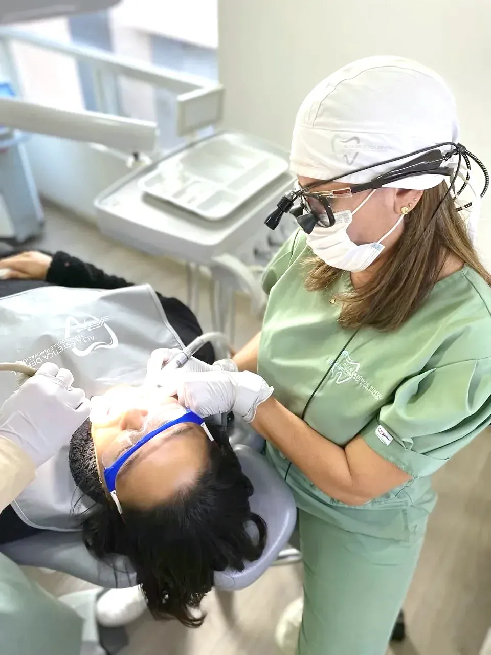 Profesional de Alta Estética Dental revisando a una paciente con lupas de magnificación.